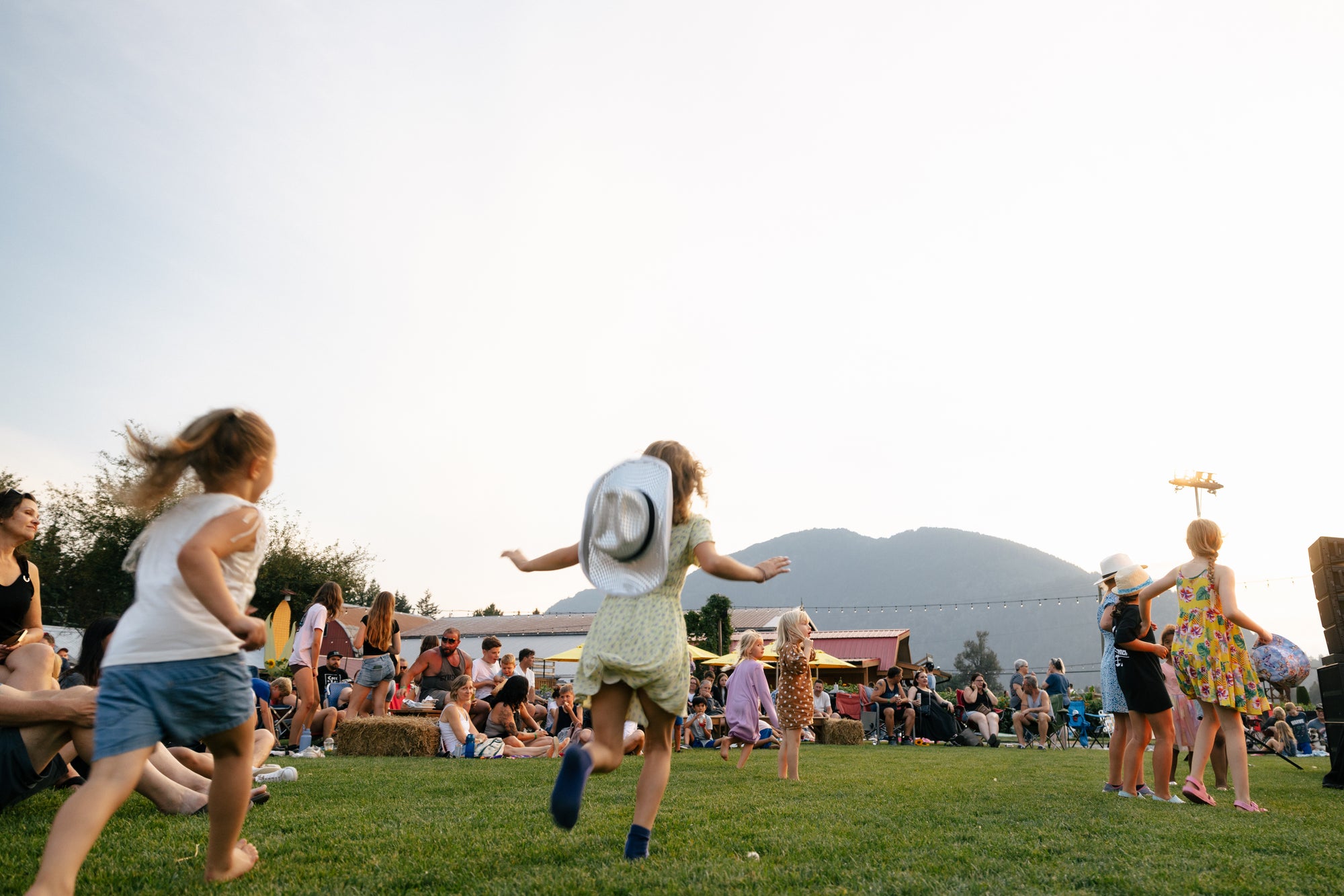 Children playing in a grassy field with mountains in the background