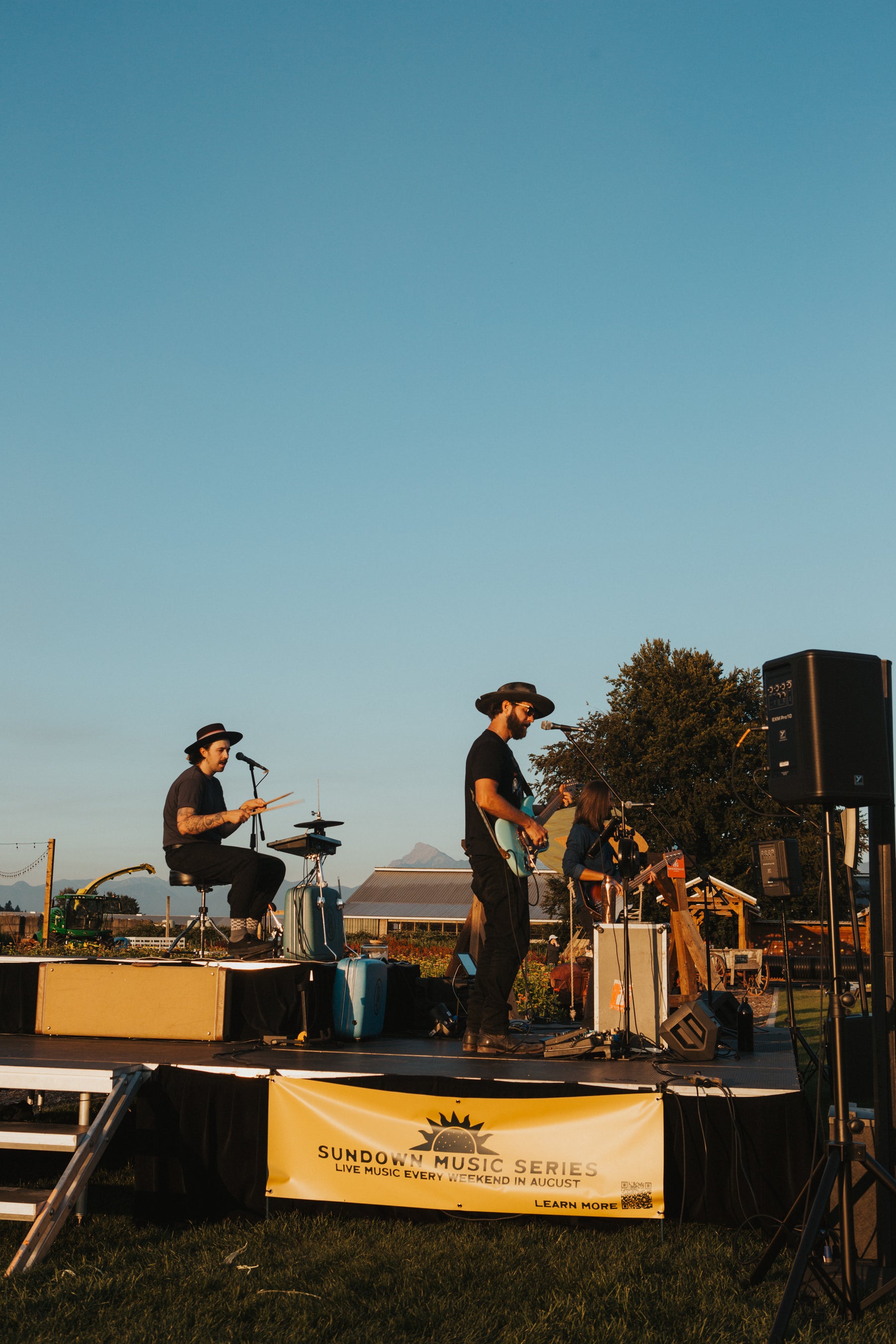 Two musicians on stage at a music festival with a clear blue sky.