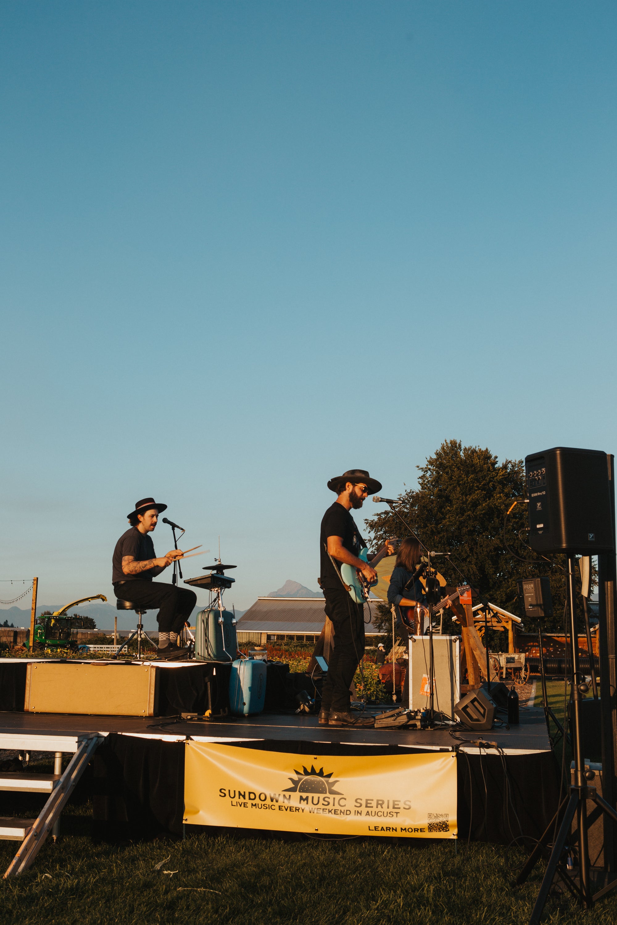 Two musicians on stage at a music festival with a clear blue sky.